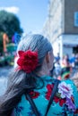 Back view of a senior female with a red flower hairband at the Hackney Carnival in London, UK