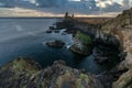 Londrangar bird cliffs and volcanic basalt rocks with dramatic blue and yellow clouds during sunset. Golden soft light on rock for