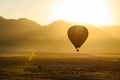 lone balloon floating, sun cresting the mountains Royalty Free Stock Photo