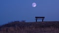 A lone bench perched atop a hill offering a perfect spot to take in the moonlit landscape and the peaceful sounds of Royalty Free Stock Photo