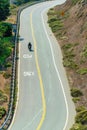 lone biker on curvy moutain road in sunlight