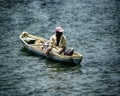 Lone black fisherman in a small boat in the ocean.