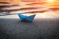 Lone blue paper boat washed up on the sandy beach at sunset Royalty Free Stock Photo