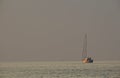 A lone boat in the sea, a sailboat, a gloomy gray sky and sea,