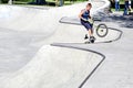A lone boy performs stunts on a bicycle at a skateboard park