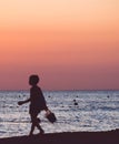 Unrecognizable lone boy walking along sea beach at sunset Royalty Free Stock Photo