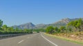 Lone car goes down the highway through coastal foothills and mountains of rural Spain. Royalty Free Stock Photo