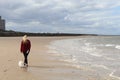 A lone Caucasian woman walking along the beach with her pet white Chihuahua dog Royalty Free Stock Photo