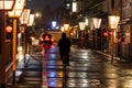 Lone cyclist and taxi on lantern lined road through Kyoto after rain