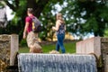 A lone duck on a city park waterfall, human silhouettes on a defocused background, selective fokus