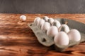 A lone egg is thrown near a package of eggs on a wooden table Royalty Free Stock Photo