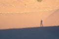 Lone explorer on the desert, casting shadow on the sand dunes on a hot sunny day.