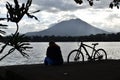 A lone fat woman enjoys the Sunday break, road bike parked beside on the mountain lake boardwalk during the height of Covid 19 pan