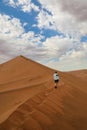 Lone hiker ascending Big Daddy dune in Namibia