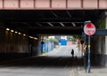 Lone female walking under bridge on deserted street in rundown area