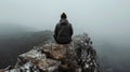 A lone figure sits atop a rocky outcrop gazing out into the vast and untamed landscape before them oblivious to the Royalty Free Stock Photo