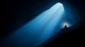 A lone figure sits in a dark cave, illuminated by a single beam of light, contemplating or using a device Royalty Free Stock Photo