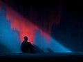 A lone figure sits on the floor silhouetted by a vibrant red and blue graph wall Royalty Free Stock Photo