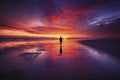 Lone Figure Standing on Deserted Beach Silhouetted Against Fiery Sunset