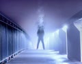 A lone figure standing on a misty path at night as his head turns into smoke