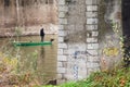 A lone fisherman in a boat under the bridge