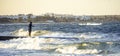 Lone fisherman catches fish on a pier in the sea with huge waves against the backdrop of the Arab city