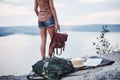 Lone girl standing near the edge of rock watching beautiful landscape with holding bag in the hands