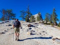 Lone Hiker with Poles Climbs Granite Hillside