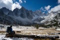 lone hiker taking a break on a log, snowcovered mountains behind