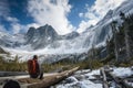 lone hiker taking a break on a log, snowcovered mountains behind