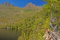 Hiker on board walkway at side of Dove Lake with Cradle Mountain`s peaks in the background at Tasmania, Australia. Royalty Free Stock Photo