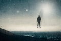 A lone hooded figure floating above a hill looking across a city at night, with UFOs floating in the sky. With a grunge, vintage e Royalty Free Stock Photo