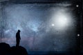 A lone hooded figure silhouetted, standing on a hill looking at a galaxy at night with UFOs floating in the sky. With a grunge, vi Royalty Free Stock Photo