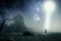 A lone hooded figure standing on a path on a spooky misty night, with a cold blue edit