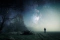 A lone hooded figure standing on a path on a spooky misty night, with a cold blue edit Royalty Free Stock Photo