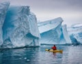 A lone kayaker among huge Arctic icebergs.