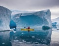 A lone kayaker among huge Arctic icebergs.