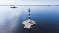 A lone lighthouse stands in the sea surrounded by water, aerial view Royalty Free Stock Photo