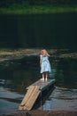 Lone little girl standing on wooden pier. Back view Royalty Free Stock Photo