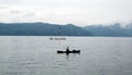 A lone man in a boat fishing on Lake Toba with the mountains in the background, Pulau Samosir. Indonesia