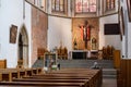 A lone man kneels in prayer at the St Adalberts Church, Wroclaw, Poland facing the altar with crucifix and vibrant stained glass Royalty Free Stock Photo