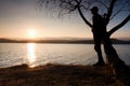 Lone man looking at colorful sunset on shore of autumn lake. Man stand bellow birch tree. Royalty Free Stock Photo