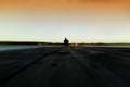 Lone man on pier orange sunset zoom