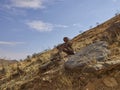 Lone man rock sculpture sitting on the side of the road