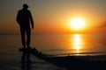 A lone man stands on the seashore during dawn. Beautiful view of the sea and the sun Royalty Free Stock Photo