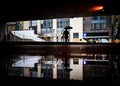 Lone man walking through dark flooded underpass under bridge big umbrella commuting to work in city centre flood water reflection Royalty Free Stock Photo