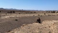 Lone Man sitting on a cliff and watches into the vast desert Royalty Free Stock Photo