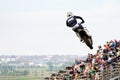 A lone motorcycle racer in the air in front of the grandstand. Selective focus