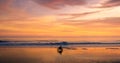 A lone motorcycle and rider driving along a beach at sunset Royalty Free Stock Photo