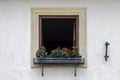 A lone open window on a white plastered wall, bright red geraniums, Royalty Free Stock Photo